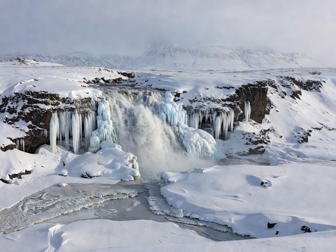 Snow and ice around a waterfall in an Icelandic winter landscape