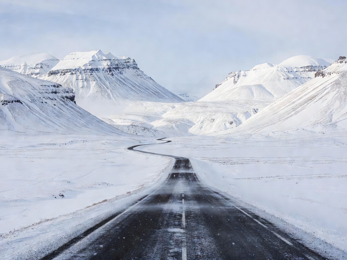 Winter road running between Icelandic mountain slopes