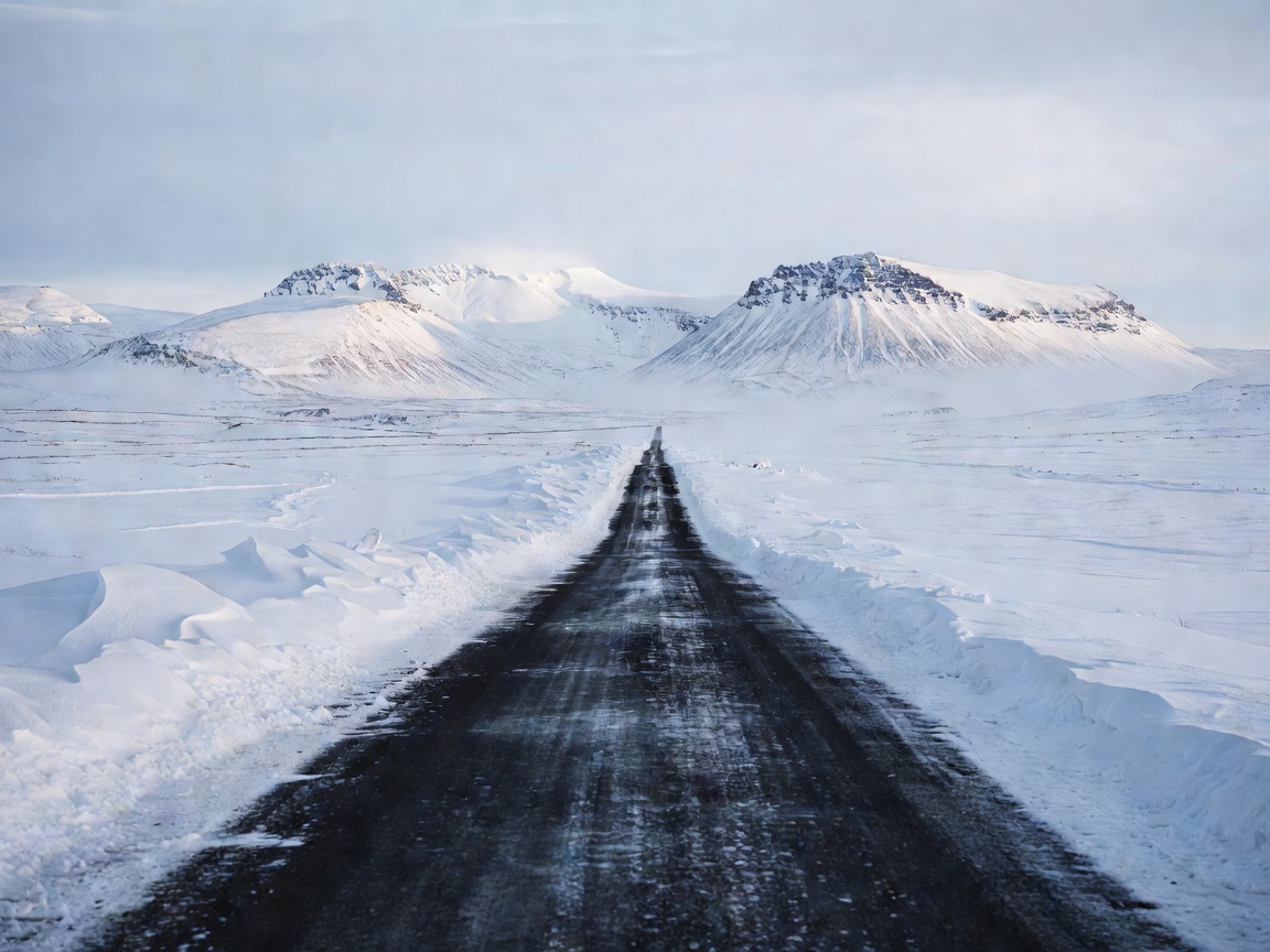 Winter road with snow along its edges and distant Icelandic mountains
