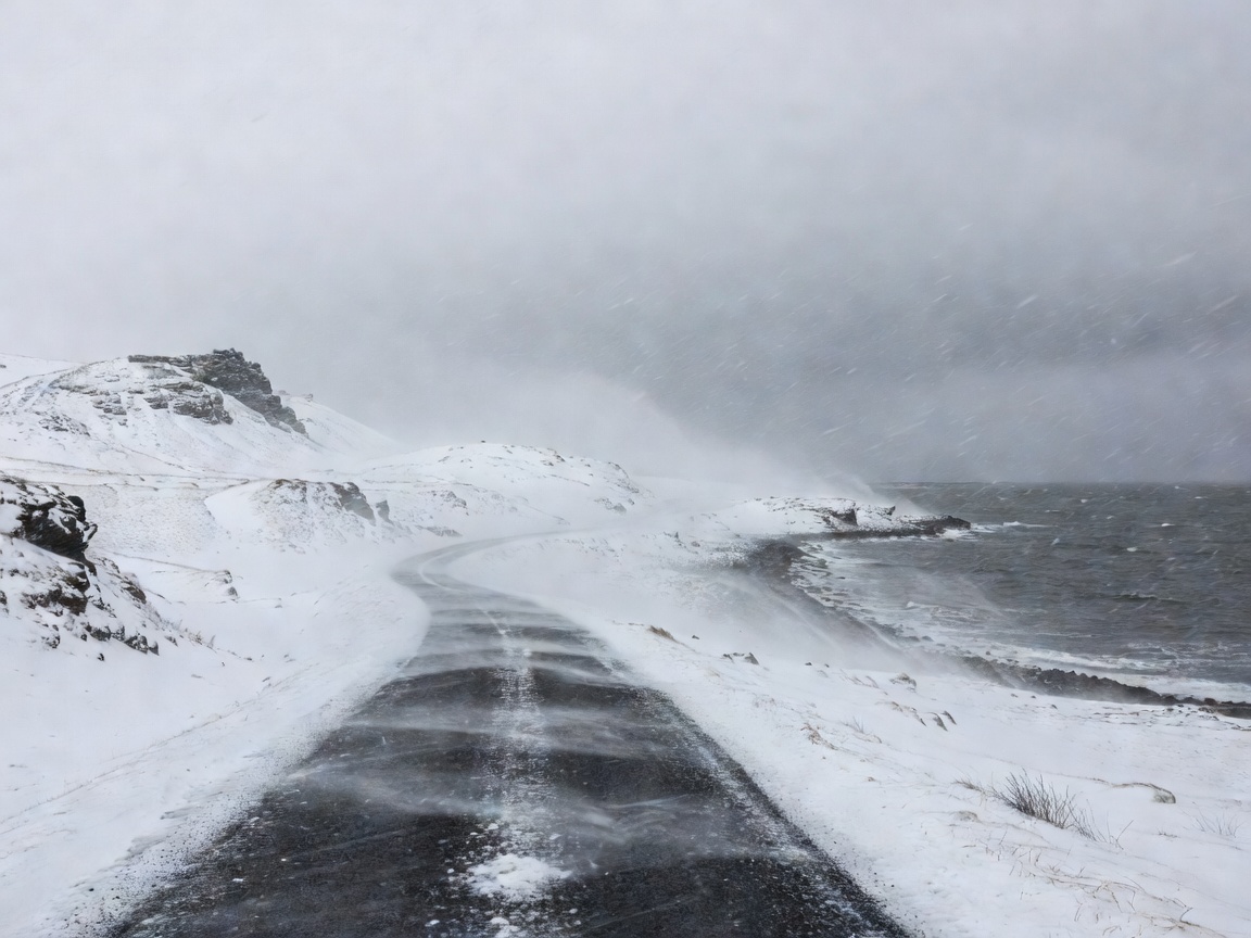 Winter squall and low cloud over an Icelandic road near a fjord